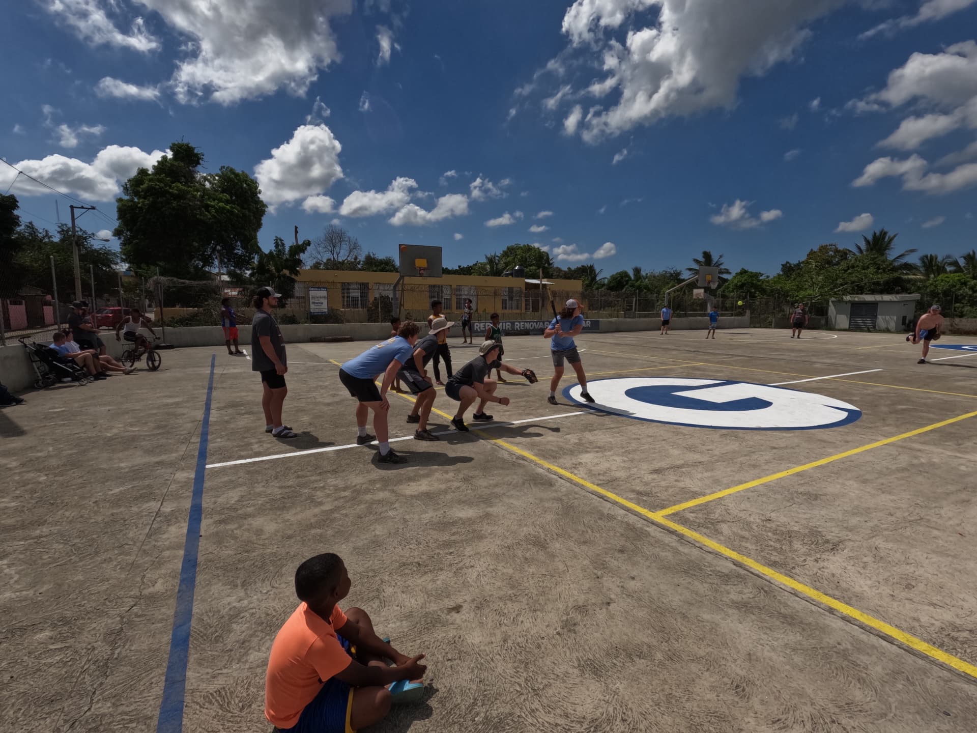 A ball game on a neighborhood court with local kids watching
