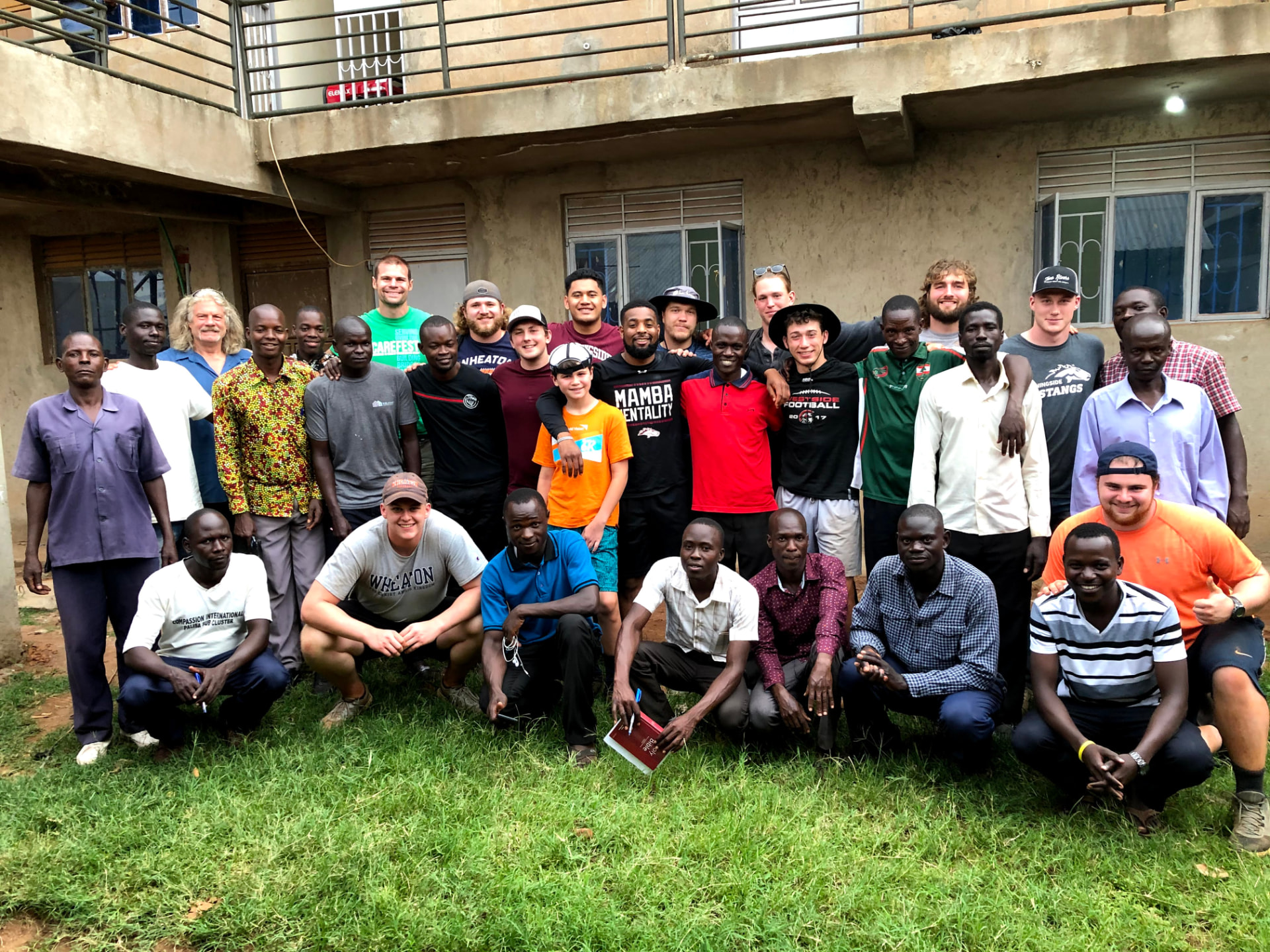 Athletes and local church partners posed together outside a community building
