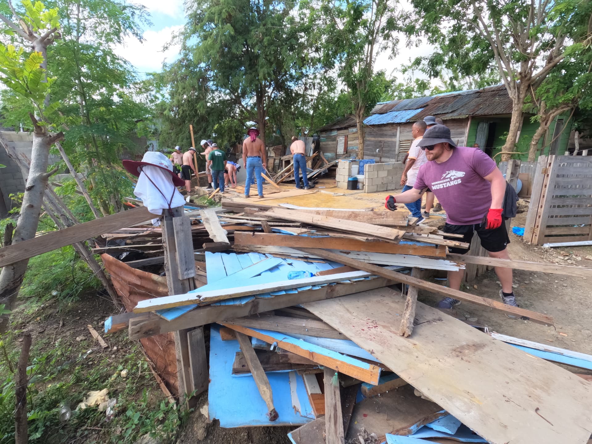 Team clearing salvaged lumber and tin from a home rebuild site